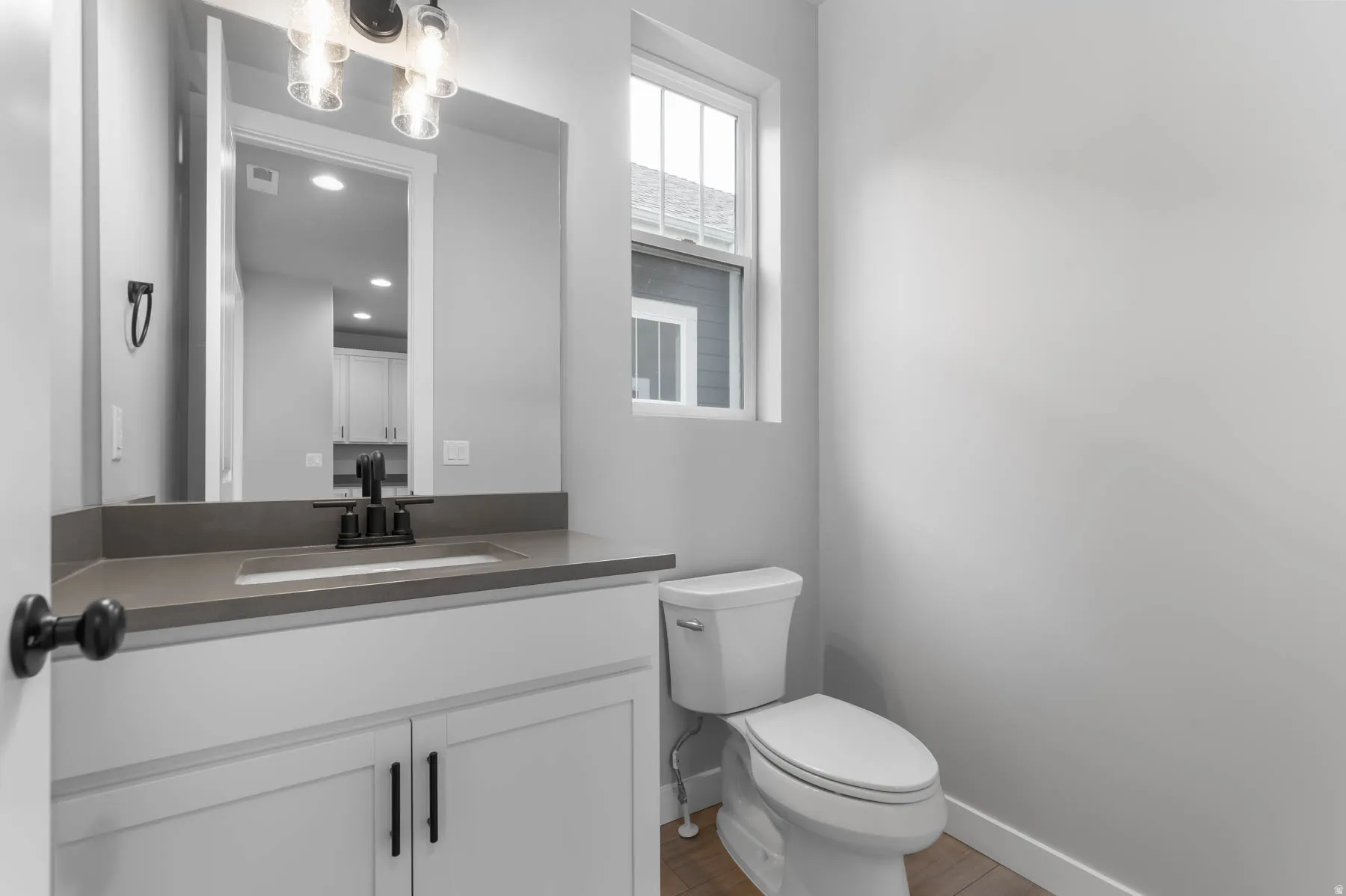 Bathroom featuring a white vanity with flat-panel doors, a dark countertop, an undermount sink, and a black faucet
