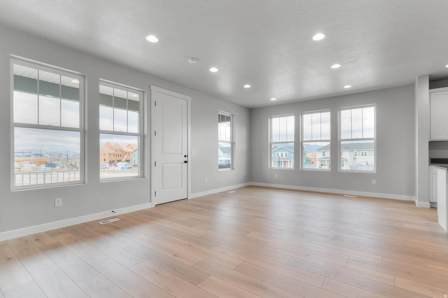 Spacious room featuring wood-finish flooring, recessed lighting, and multiple large windows
