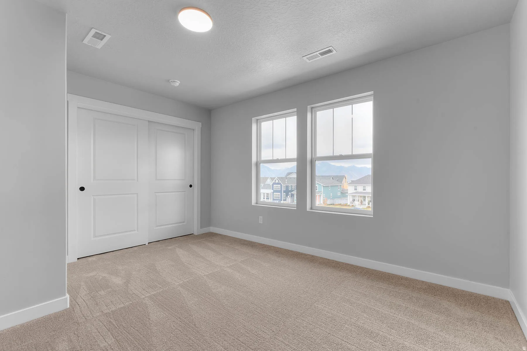 Room featuring light gray walls, two double-hung windows, and beige carpet