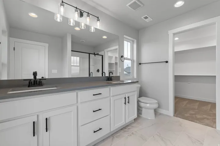 Double vanity with stone countertop and integrated sinks, matte black fixtures, and a six-light bar sconce