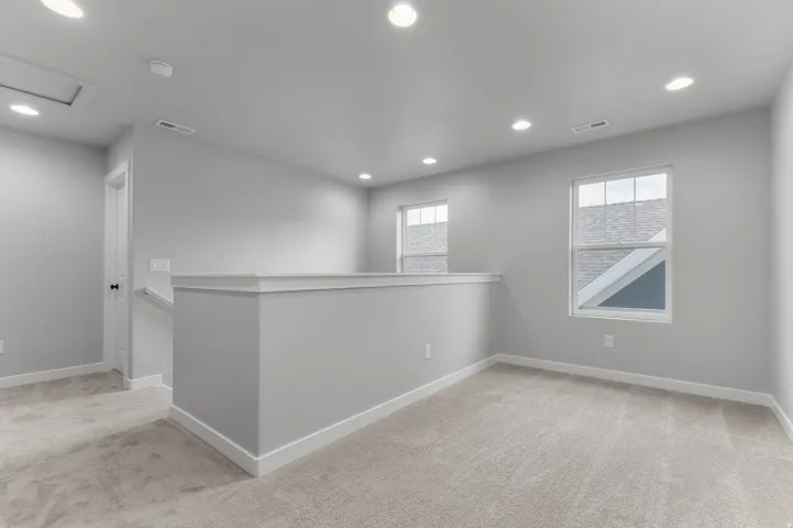 Open loft area featuring neutral carpeting and recessed lighting