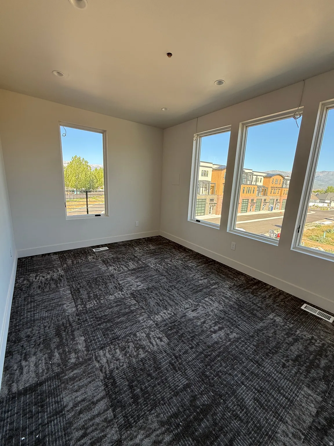 Spacious room featuring broadloom carpet, recessed lighting, and multiple windows providing ample natural light