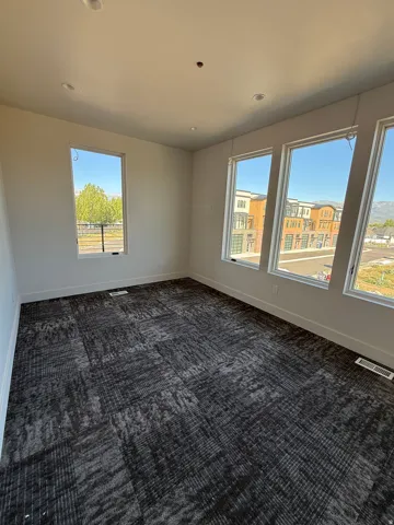 Spacious room featuring broadloom carpet, recessed lighting, and multiple windows providing ample natural light