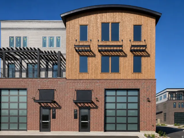 Contemporary building facade featuring a brick base, wood-finish siding, and a curved roofline