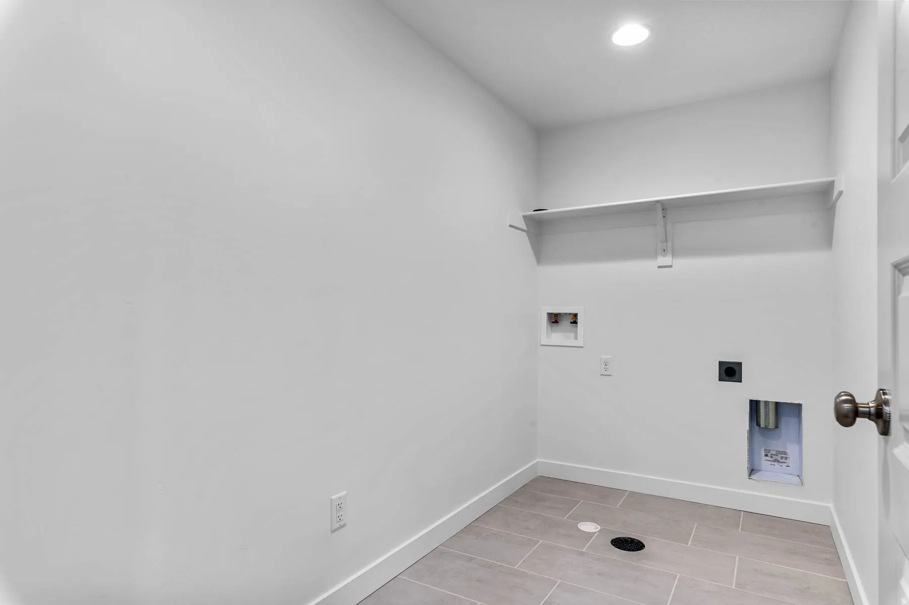 Dedicated laundry room featuring tile flooring, white walls, and a built-in shelf