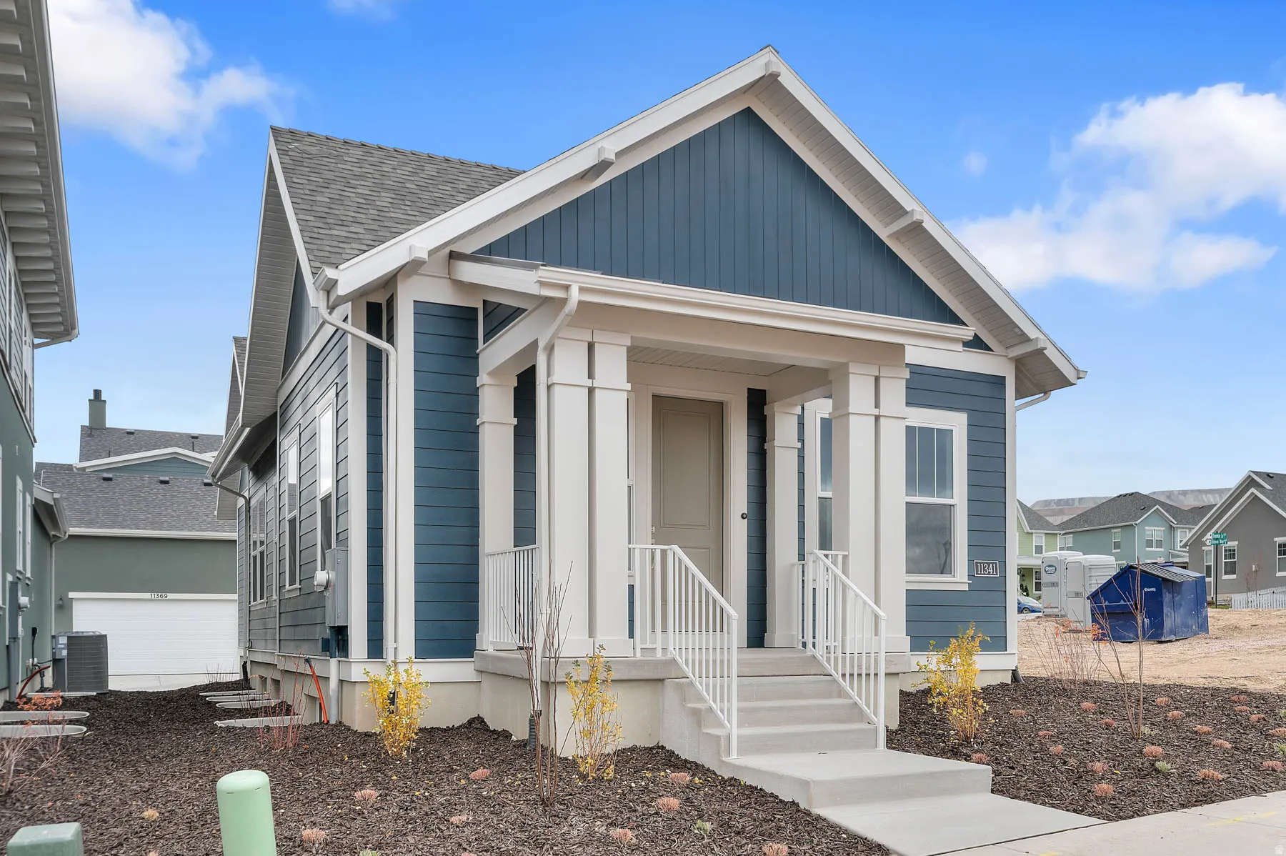 Contemporary residence featuring a striking blue siding exterior with white trim and a prominent front porch