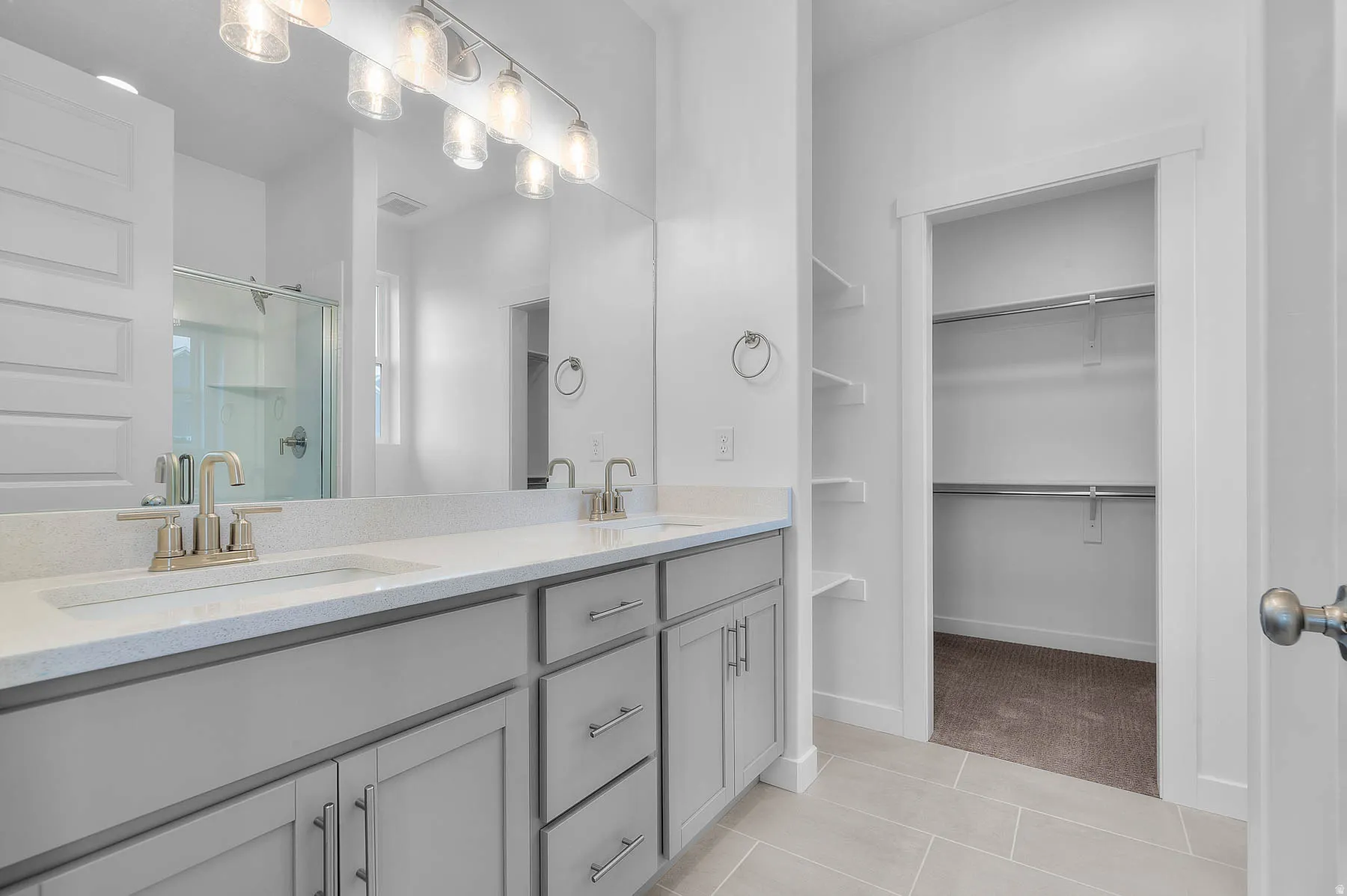 Double vanity with light gray cabinetry, brushed nickel hardware, and a light-toned countertop