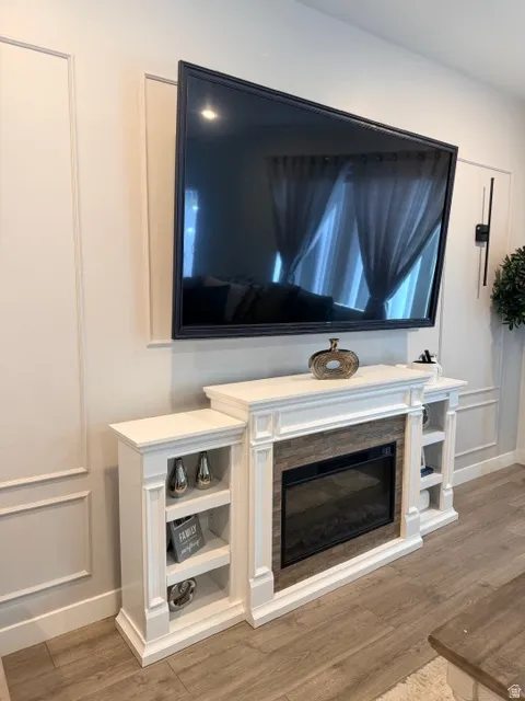 White fireplace surround with integrated shelving, a wood-finish tile accent, and a built-in electric fireplace