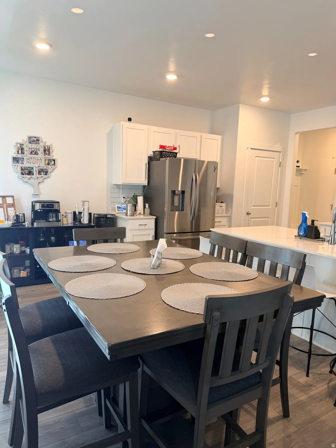 Kitchen and dining area featuring wood-finish flooring, recessed lighting, white shaker-style cabinetry, and a white subway tile backsplash
