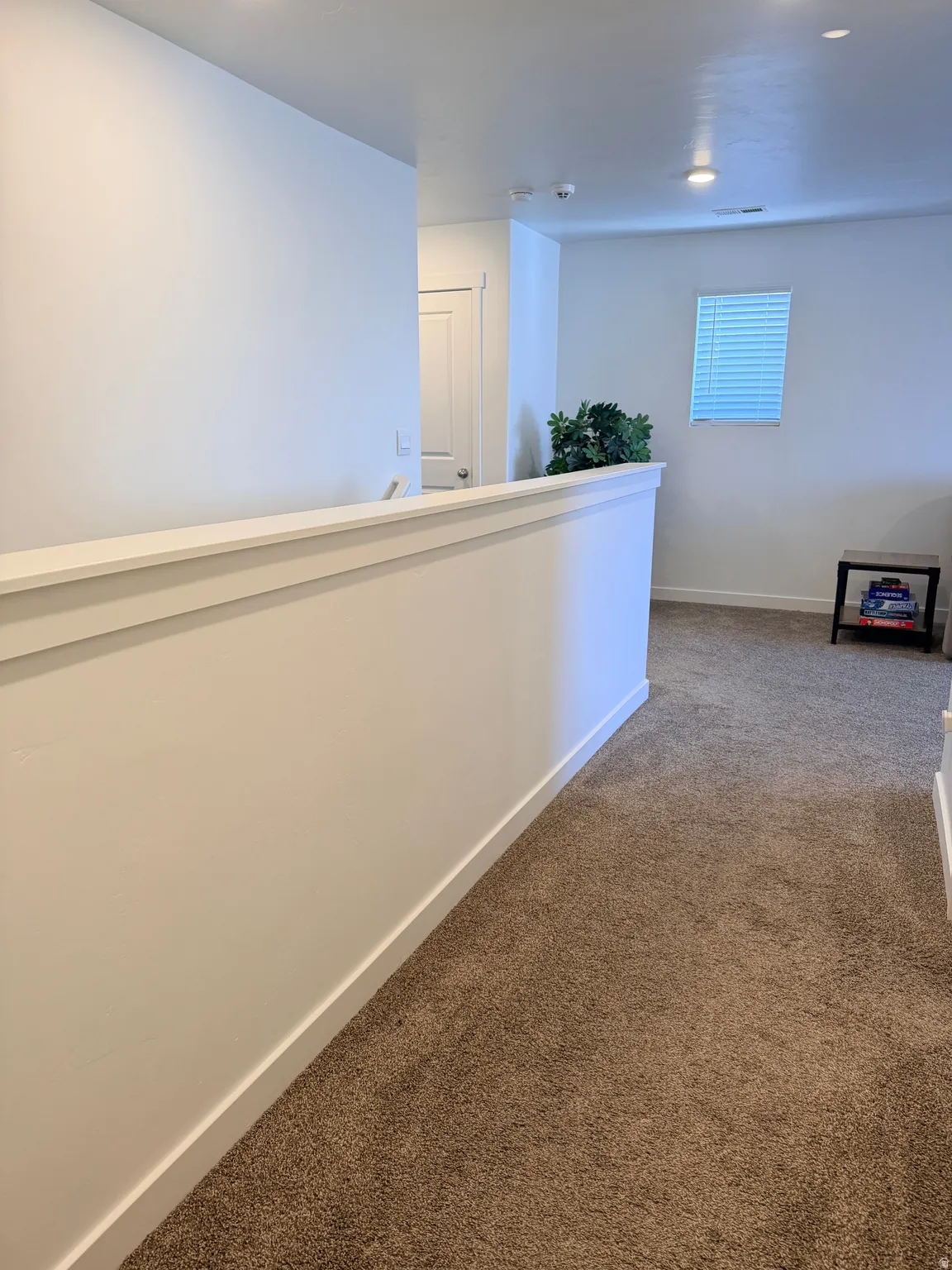 Upper-level hallway with neutral carpeting and white wall finishes