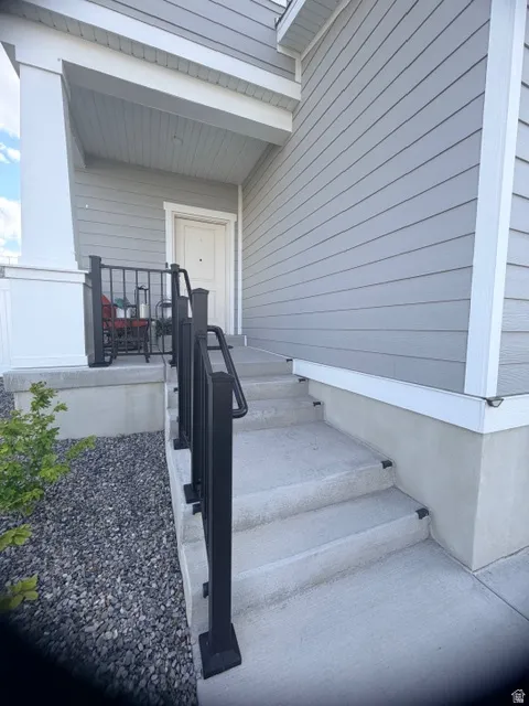 Inviting covered front entrance featuring durable concrete steps with modern black railings