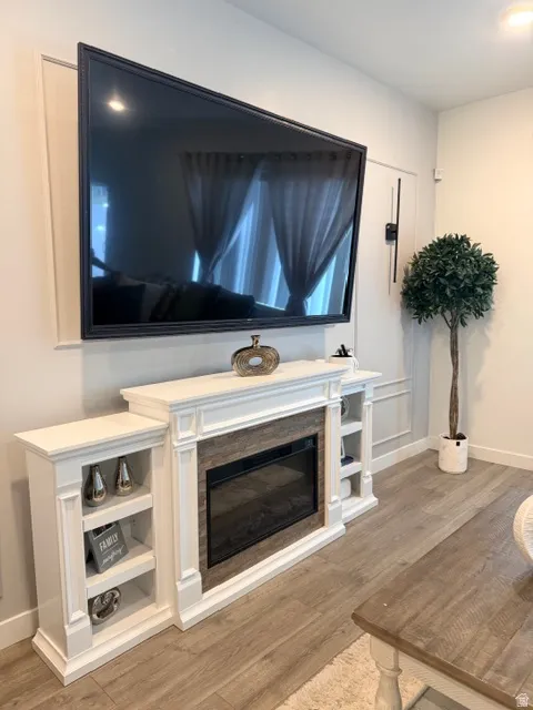 Living area featuring a white electric fireplace with integrated shelving, a wood-finish surround, and a wall-mounted display