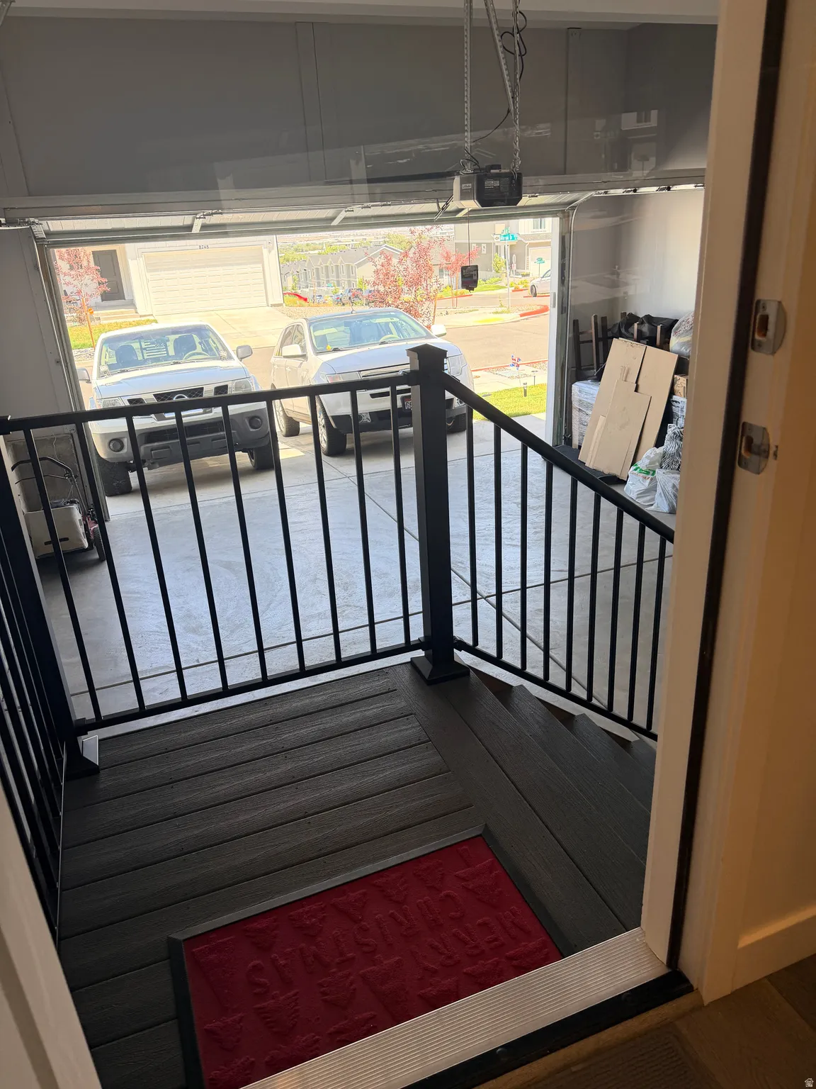 Garage interior featuring a composite landing with a black metal railing, leading to a concrete floor