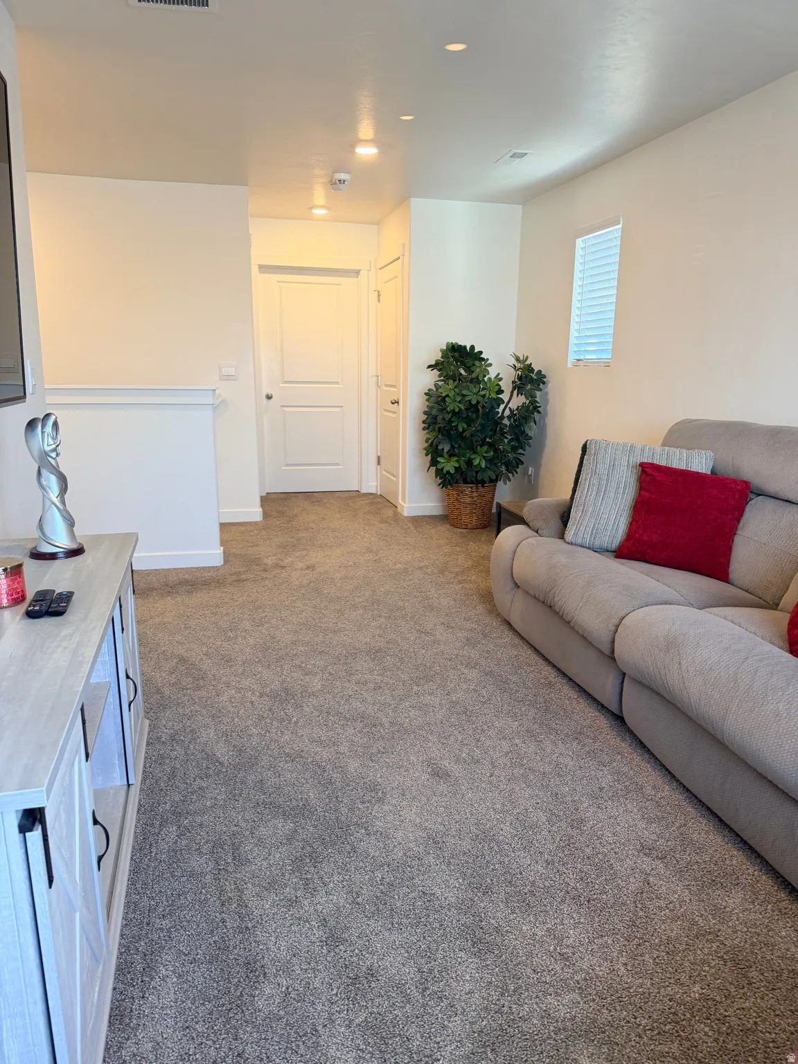 Open concept room featuring neutral tone walls, recessed lighting, a window with horizontal blinds, and grey carpet flooring