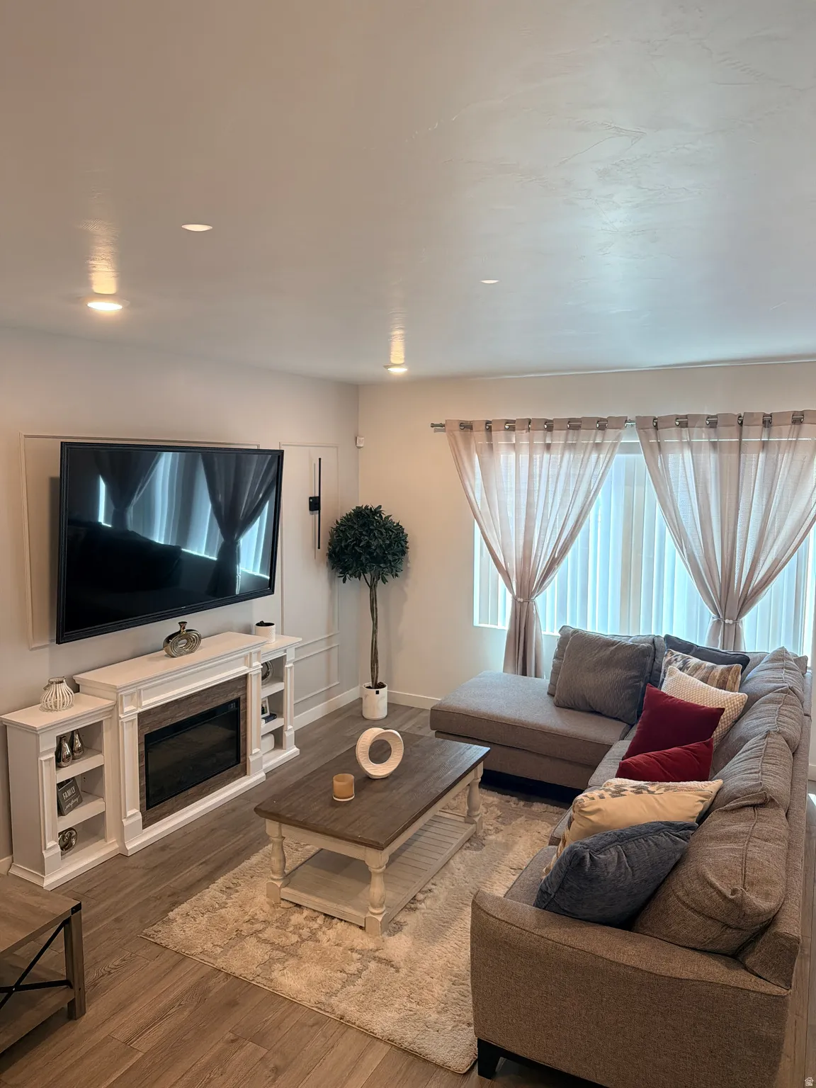 Bright living area featuring wood-finish flooring, recessed lighting, and a built-in electric fireplace with integrated shelving