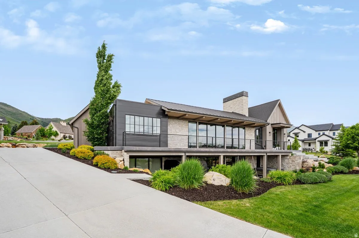 Modern architectural residence featuring extensive glazing, a stone facade, and dark horizontal siding