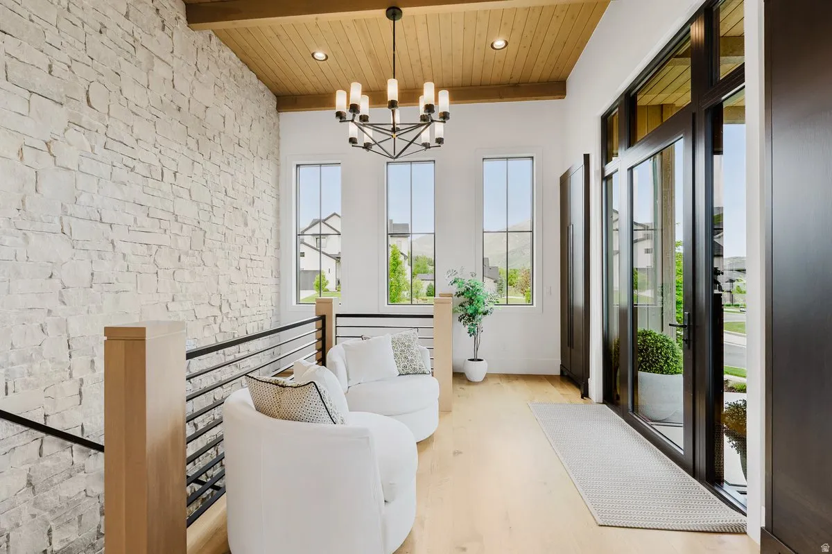 Spacious entryway featuring a stone accent wall, wood-finish flooring, and a beamed ceiling