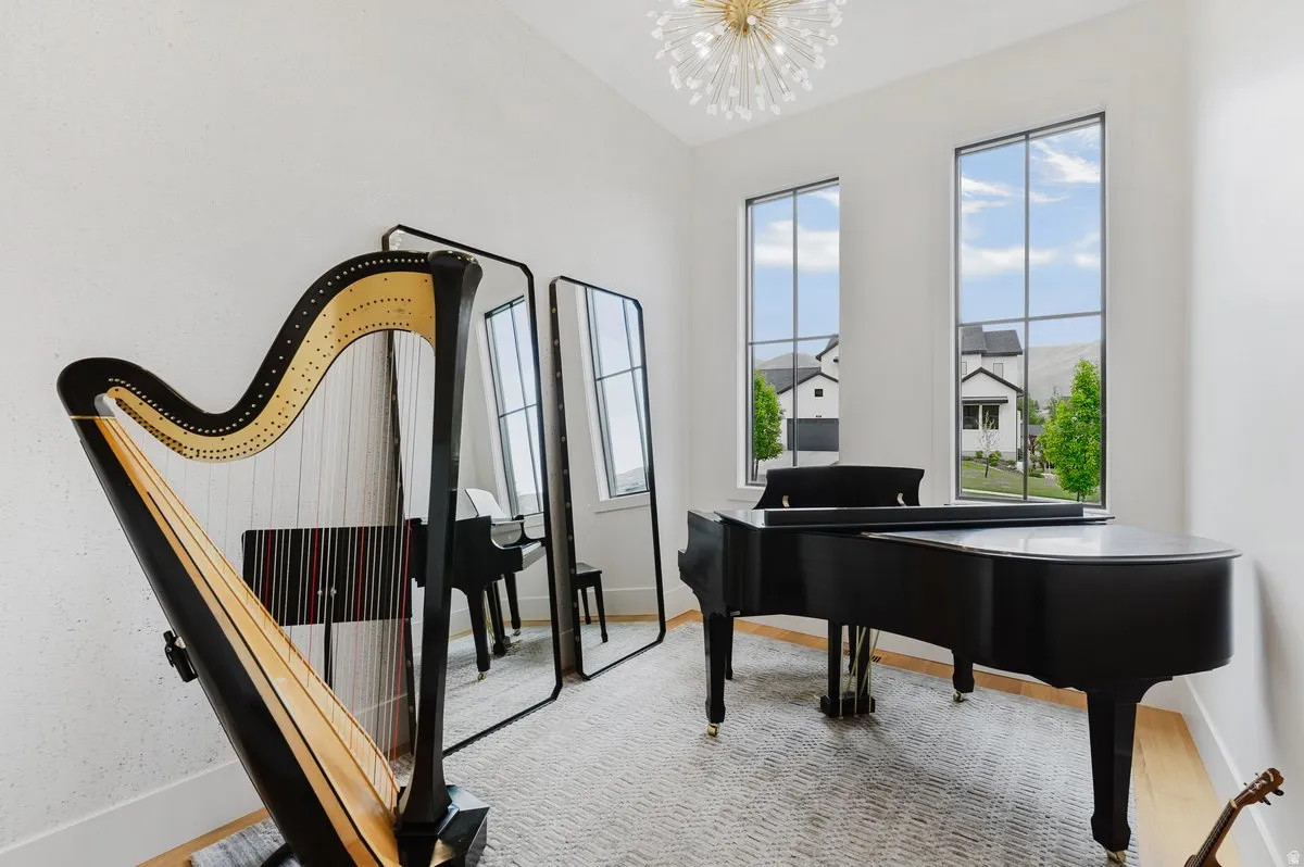 High ceilings featuring a contemporary chandelier, two tall windows with grid patterns, and light wood-finish flooring