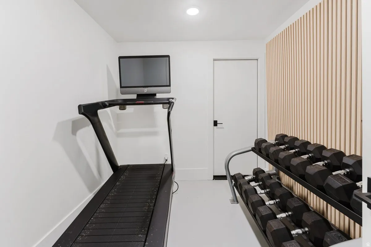Dedicated fitness space featuring clean white walls, recessed lighting, and a modern slat wall accent