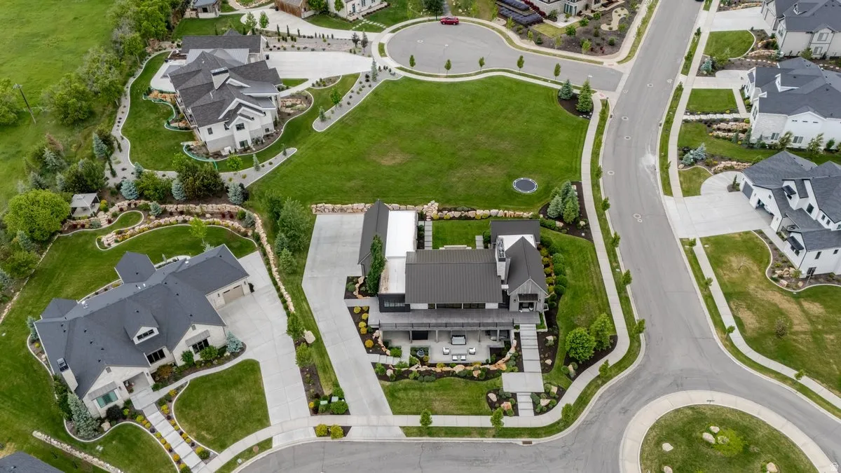 Modern residence with a dark metal roof, extensive hardscaping, and a spacious concrete driveway