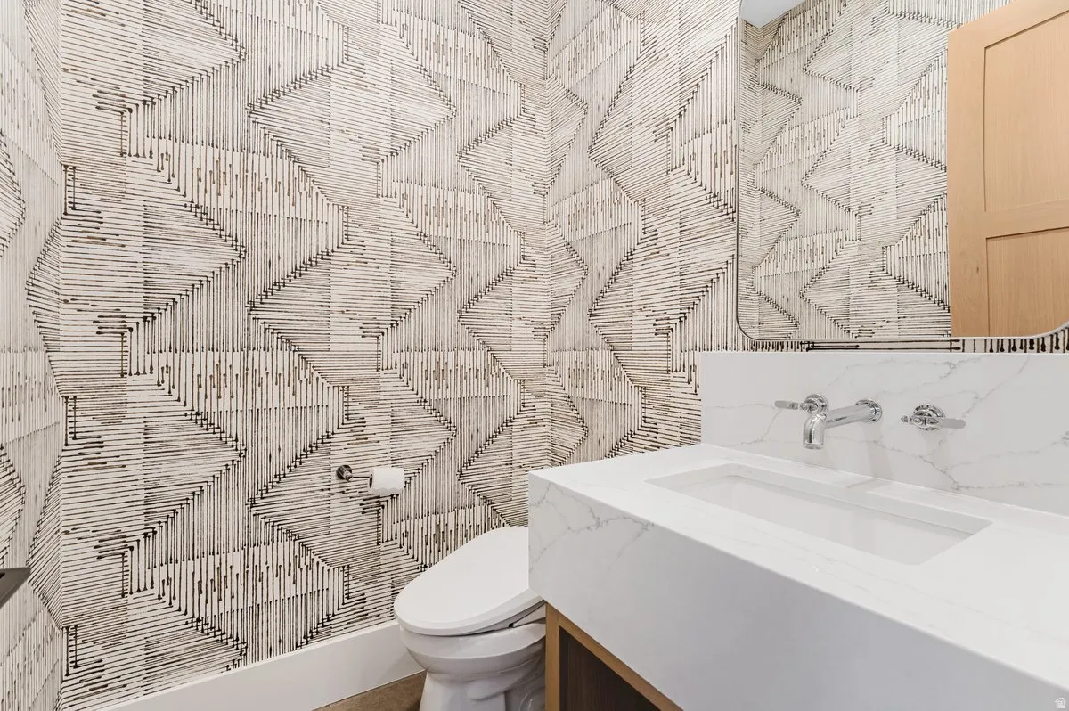 Powder room featuring a floating vanity with an integrated rectangular sink, wall-mounted chrome fixtures, and a coordinating backsplash
