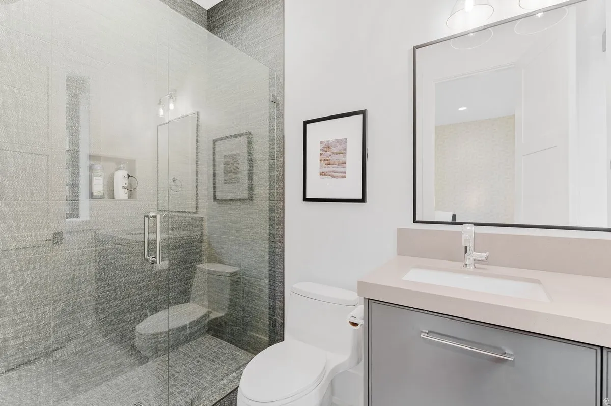 Glass-enclosed shower with gray tiled walls and floor, featuring a built-in shower niche