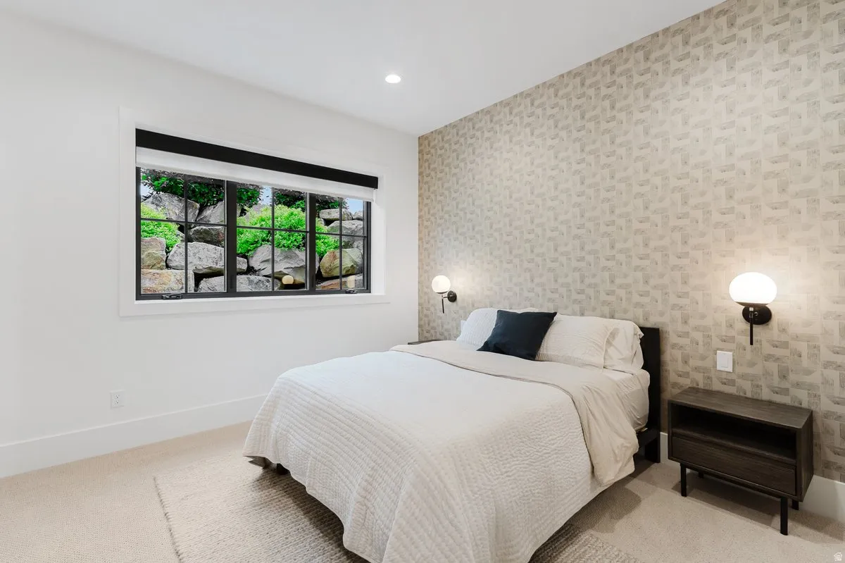 Bedroom featuring a patterned accent wall, recessed lighting, and wall-mounted sconces