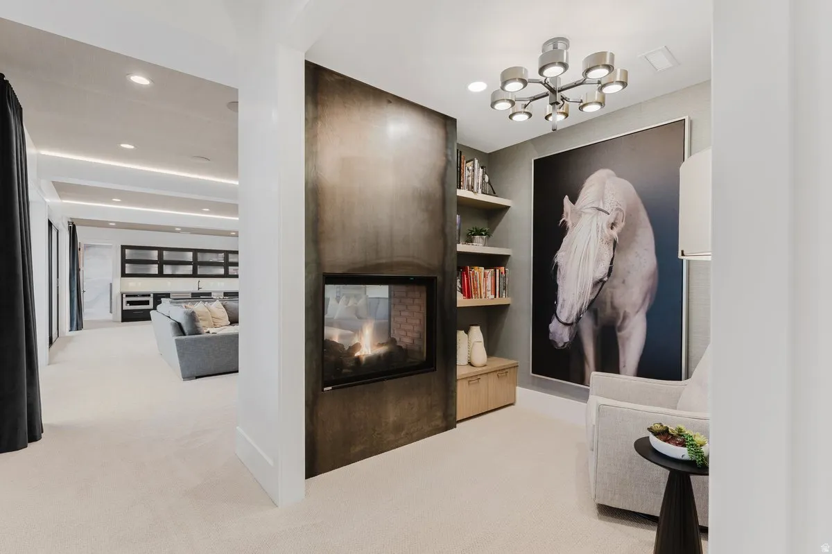 Contemporary fireplace with a dark metal surround, integrated shelving, an overhead light fixture, and plush carpeting