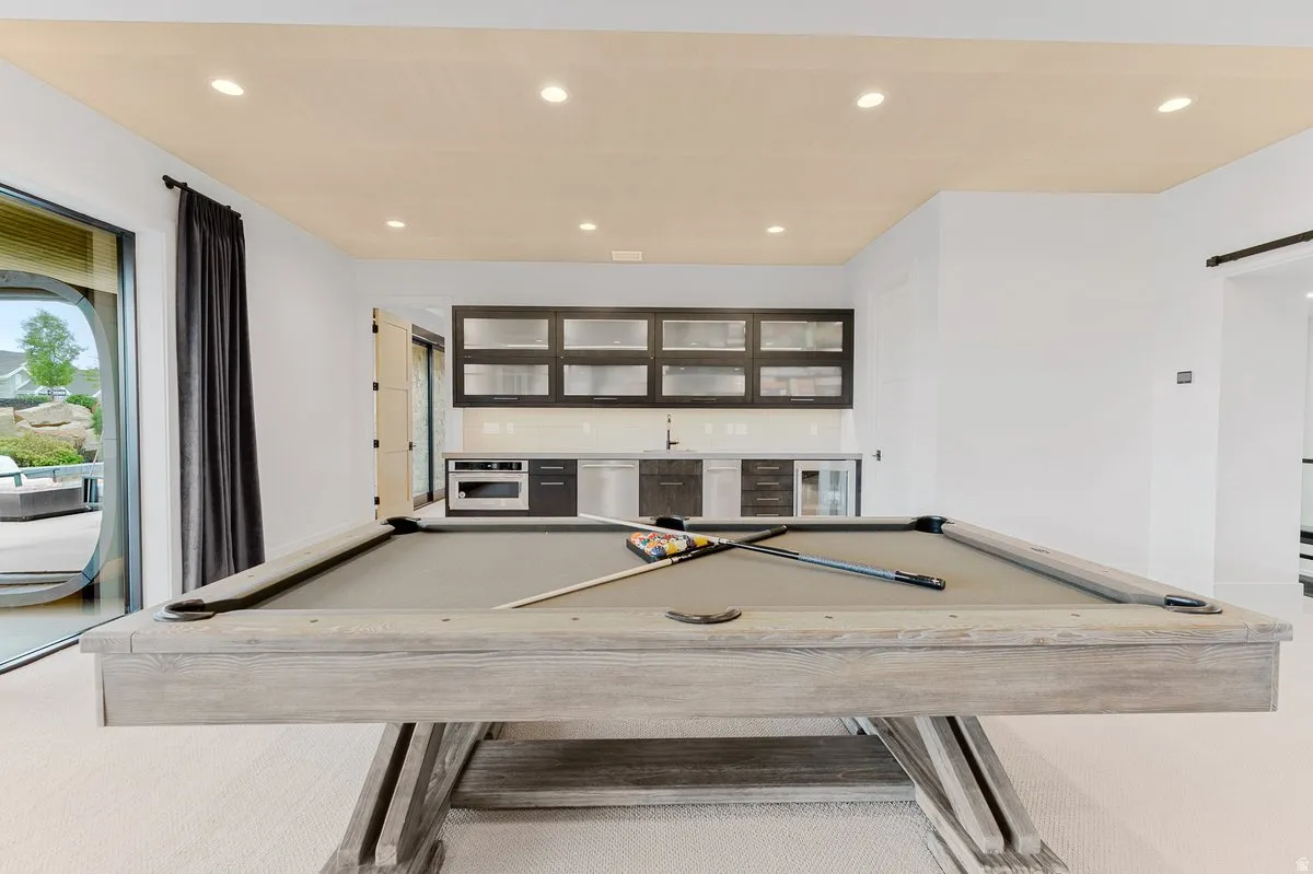 Recreation room featuring a pool table, a built-in wet bar with cabinetry and appliances, recessed lighting, and a sliding glass door leading to the exterior