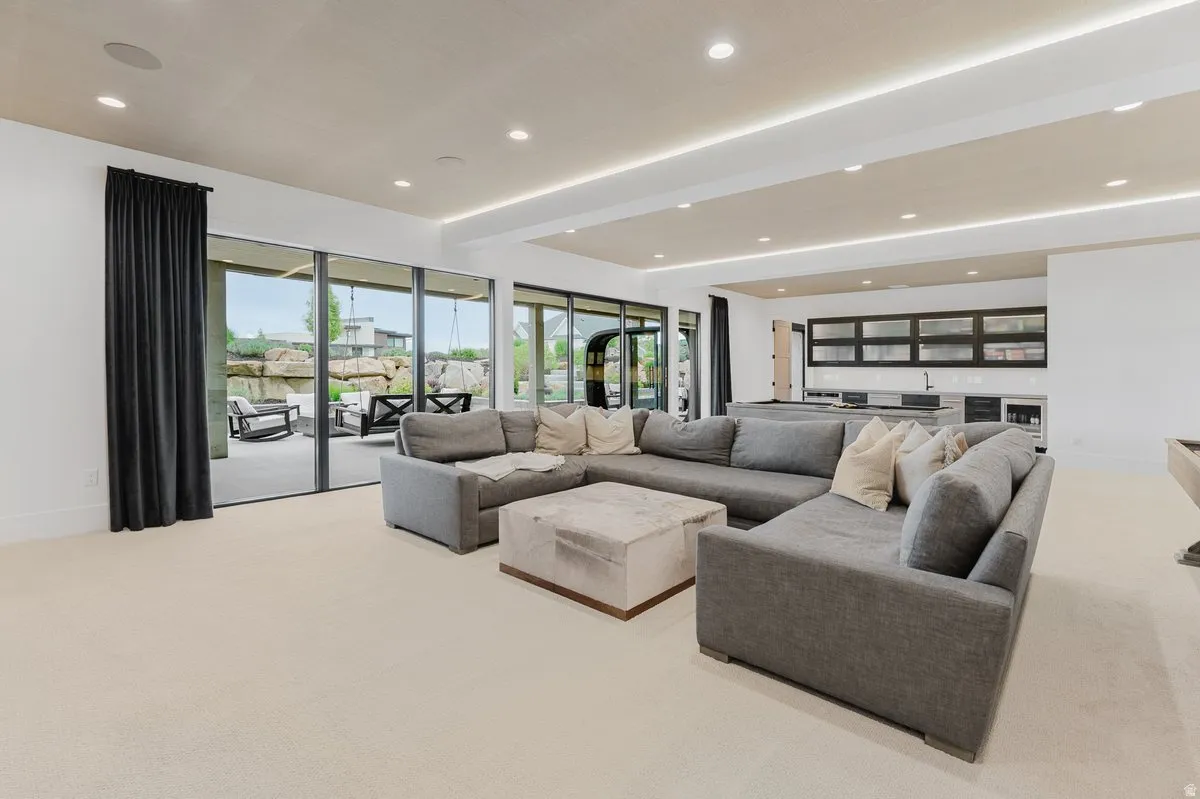 Open-concept entertainment space featuring recessed lighting, a built-in wet bar with cabinetry, and large sliding glass doors leading to an outdoor patio with rock landscaping