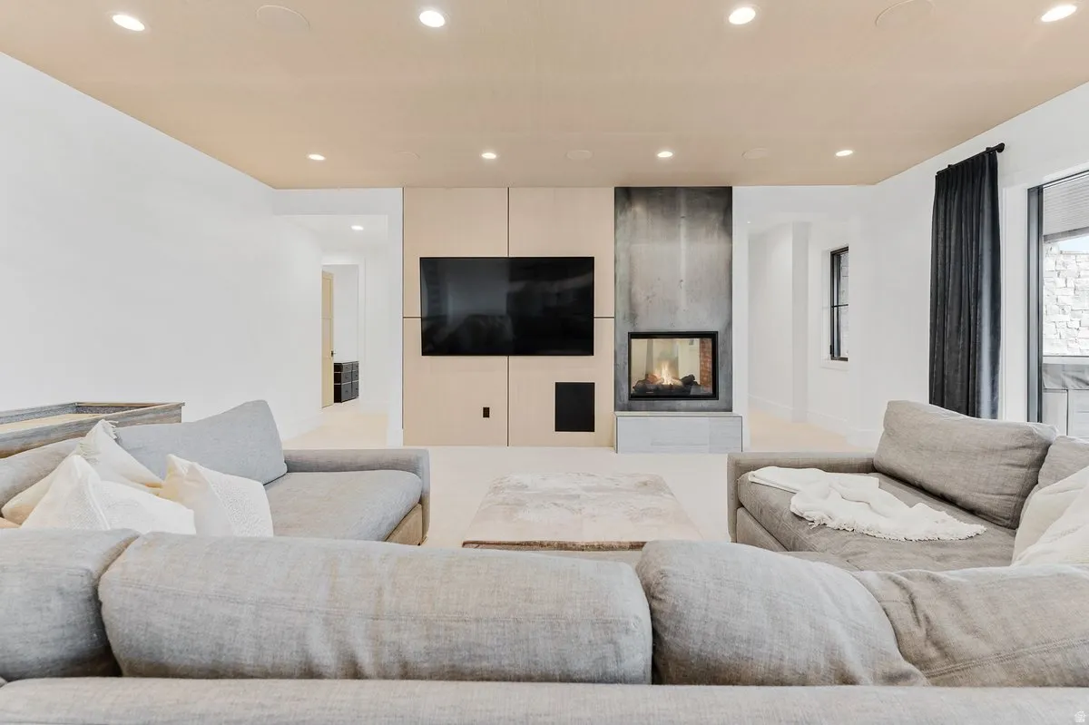 Living area featuring a contemporary linear fireplace with a stone hearth, recessed lighting, and large windows with dark drapery
