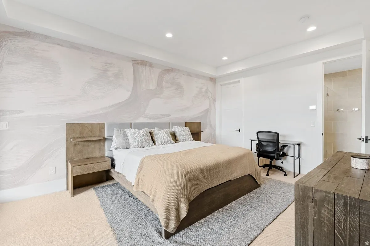 Recessed lighting illuminates a space featuring a decorative accent wall and light-toned carpeting