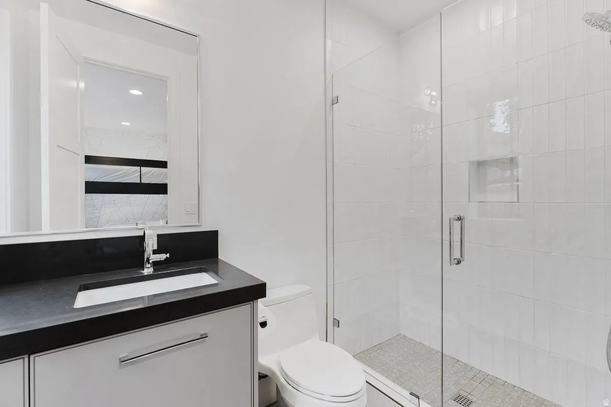Full bathroom featuring a frameless glass shower enclosure, a recessed shower niche, and mosaic tile shower flooring