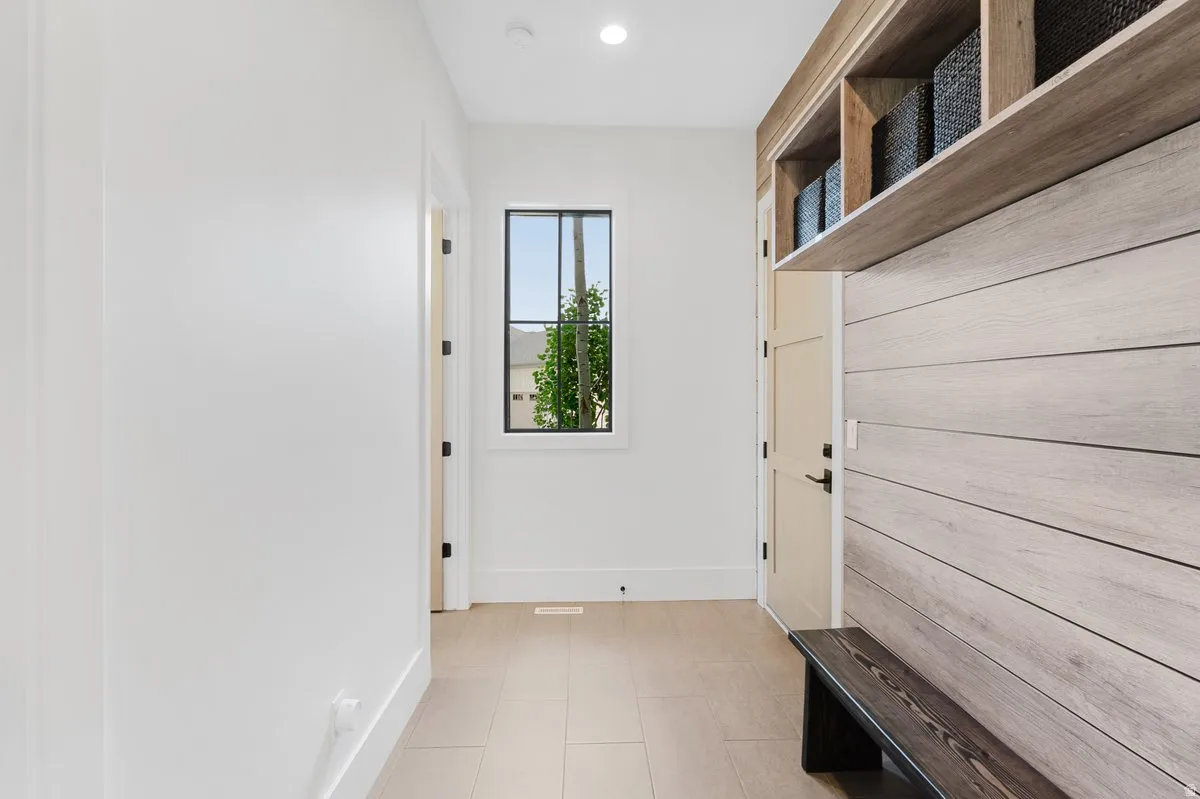 Entryway featuring a built-in bench, overhead shelving, and wood-finish accent wall