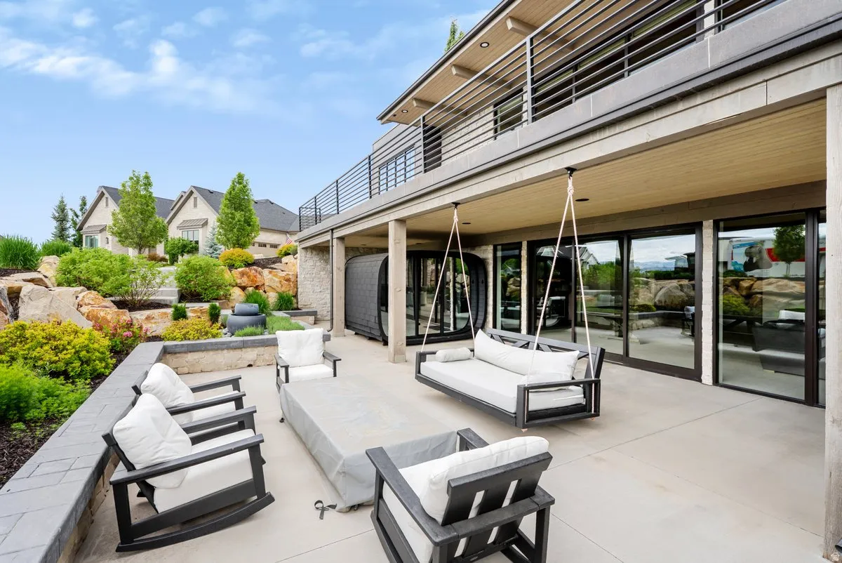 Expansive outdoor patio featuring a concrete surface, a ceiling-mounted swing bed, and a series of floor-to-ceiling glass sliding doors