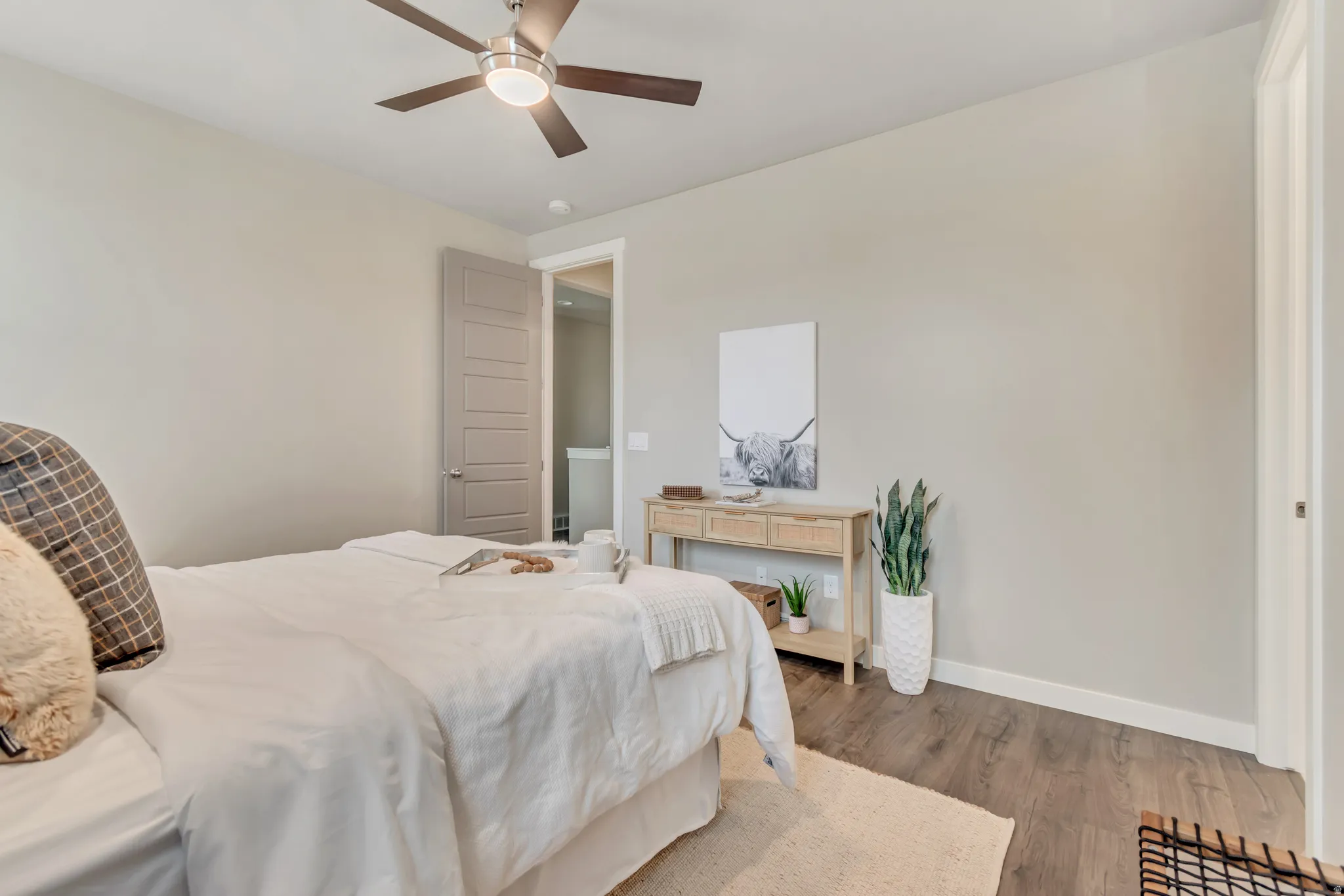 Bedroom featuring wood-finish flooring, light neutral wall paint, and a ceiling fan with integrated lighting