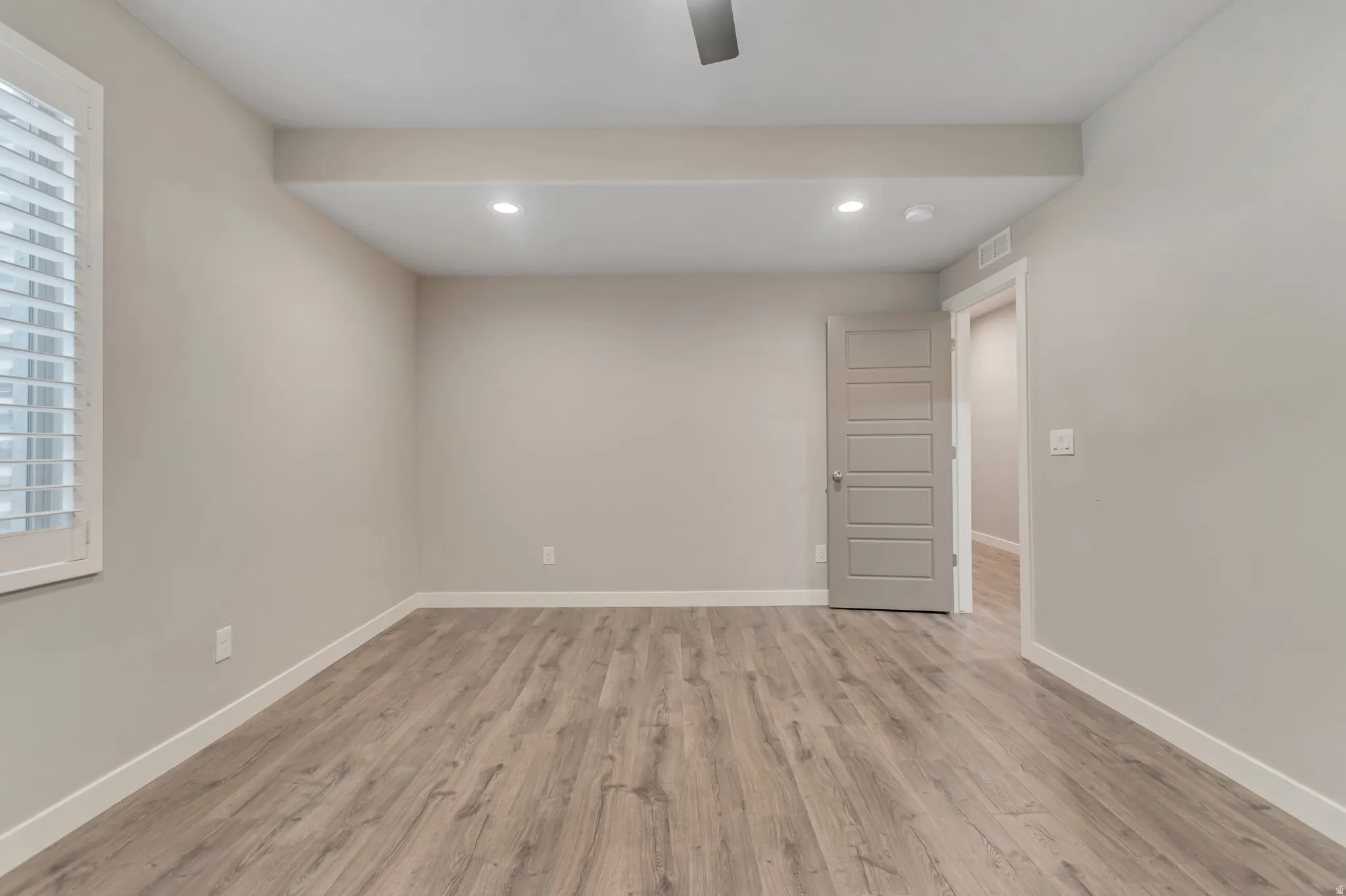 Spacious room with wood-finish flooring, neutral-toned walls, and white baseboards