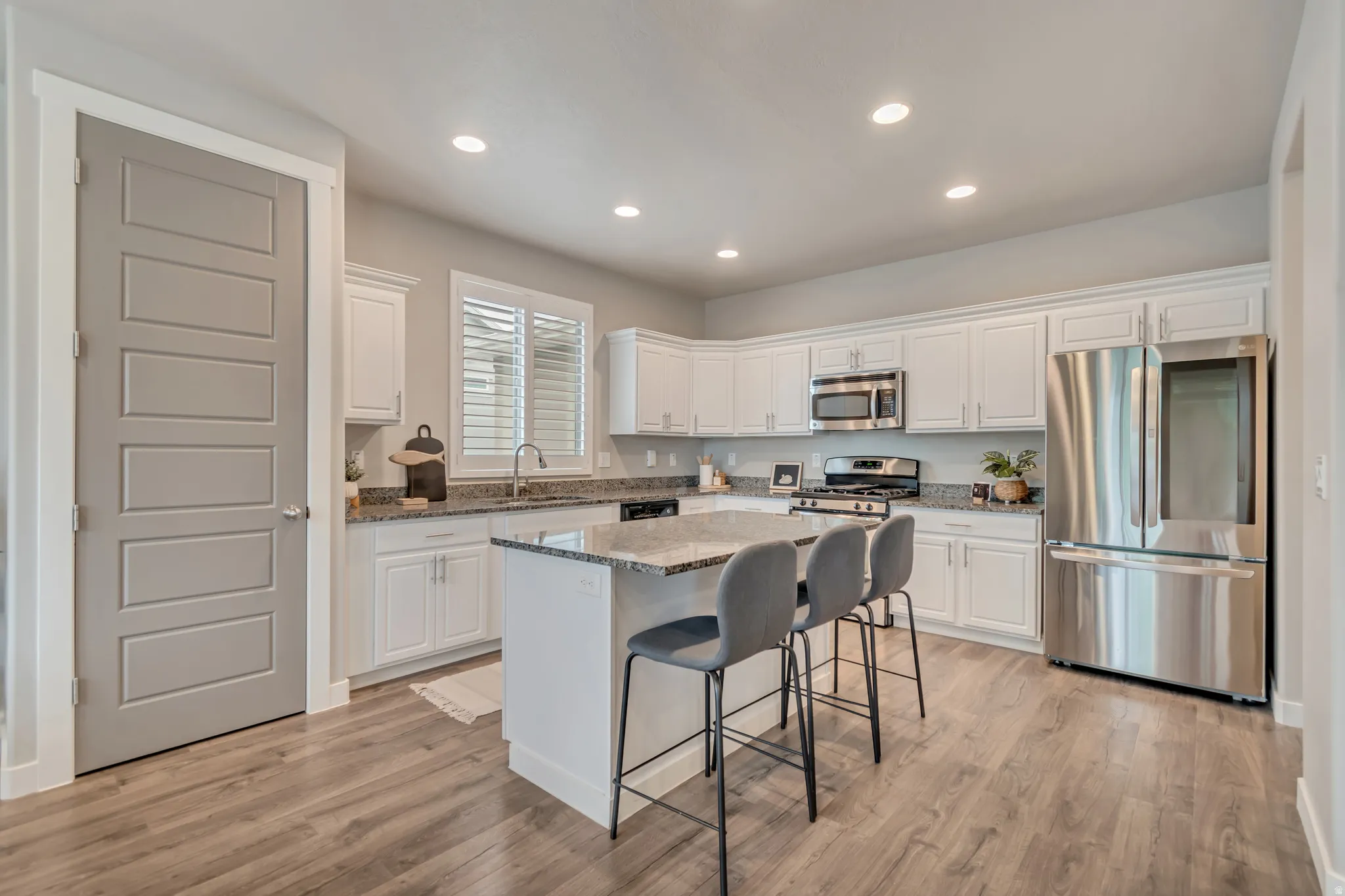 Modern kitchen featuring white cabinetry, granite countertops, and stainless steel appliances