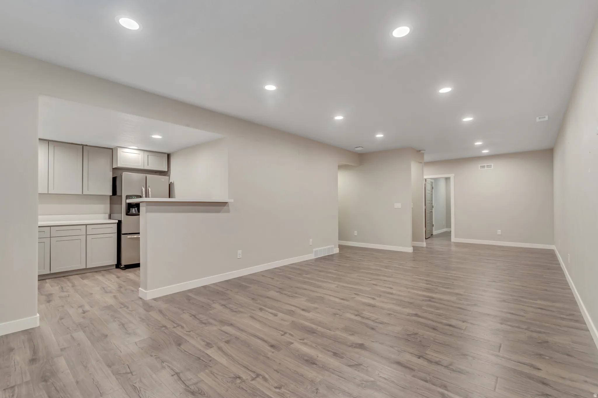 Open-concept living area featuring wood-finish flooring, recessed lighting, and a neutral color palette
