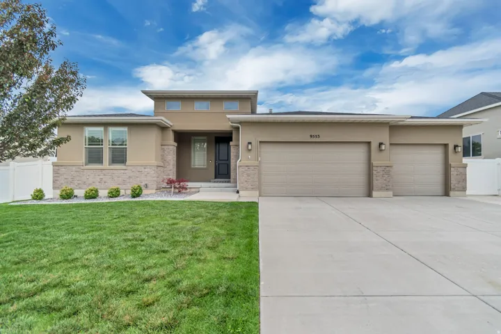 Contemporary stucco exterior with stone accents, featuring an attached two-car garage and a separate single-car garage