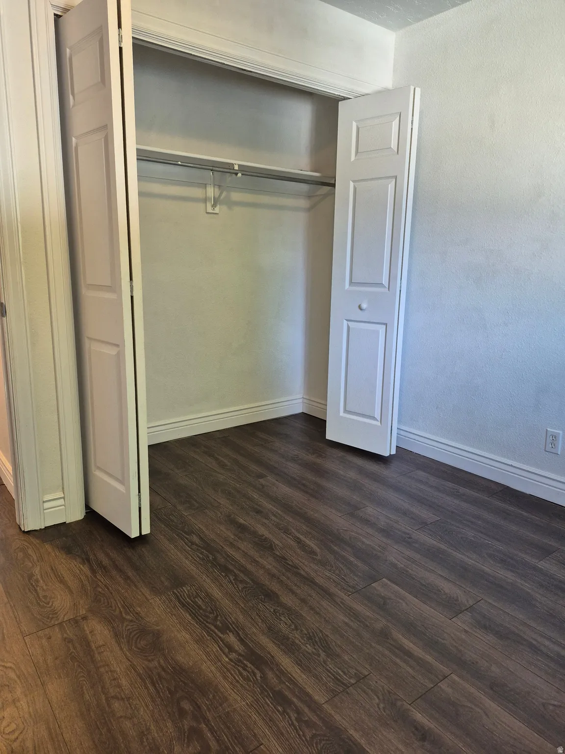 Spacious closet featuring bi-fold doors, hanging rod, and upper shelf