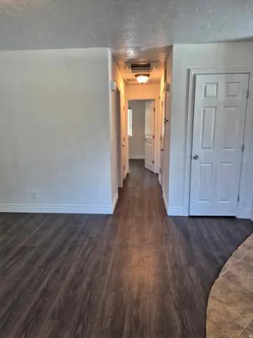 Hallway featuring wood-finish flooring, white paneled doors, and a flush-mount ceiling light