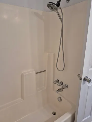 Bathtub/shower combination featuring a multi-function showerhead, integrated soap dish, and chrome fixtures