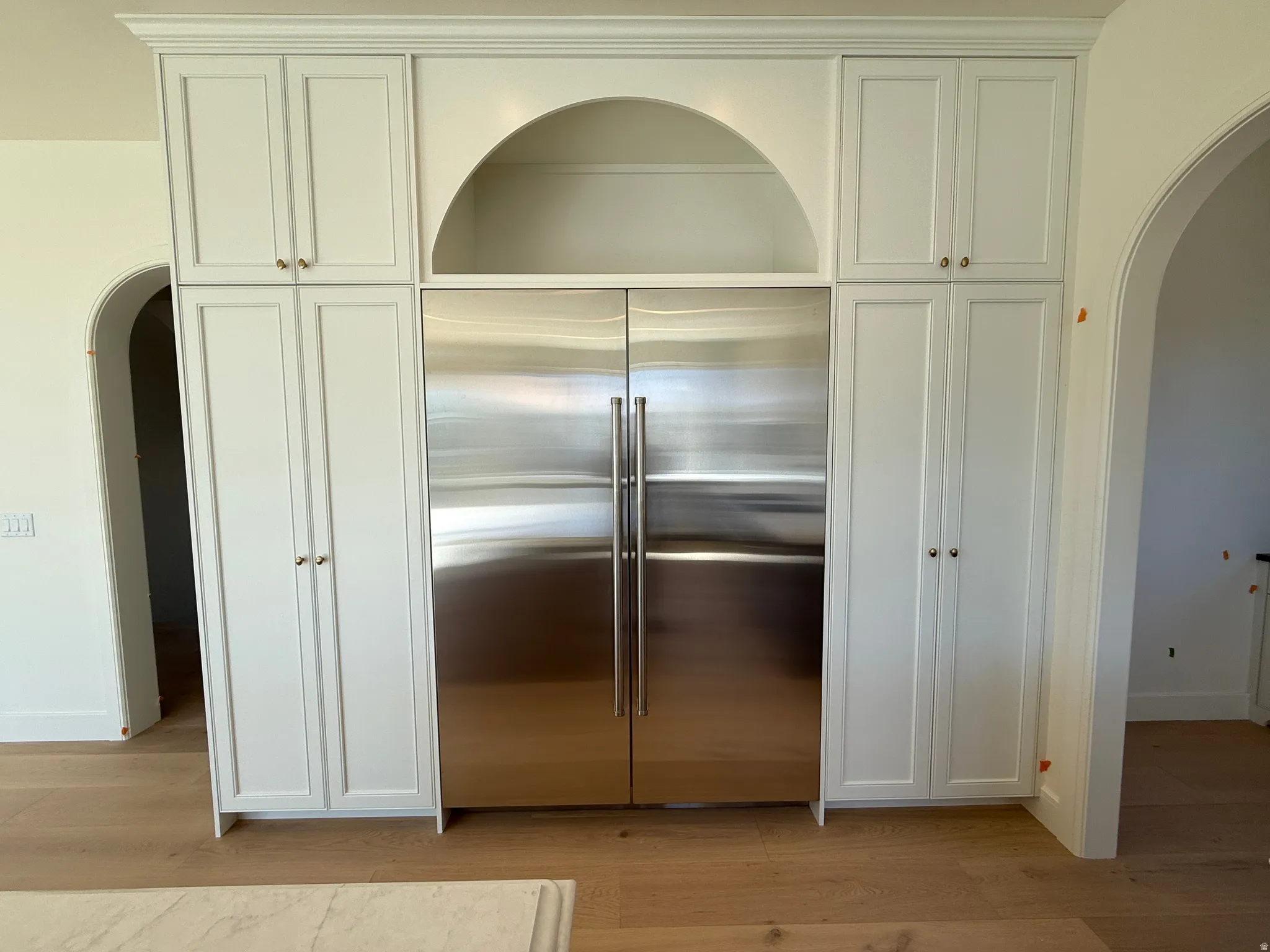 Integrated stainless steel refrigerator framed by custom white cabinetry