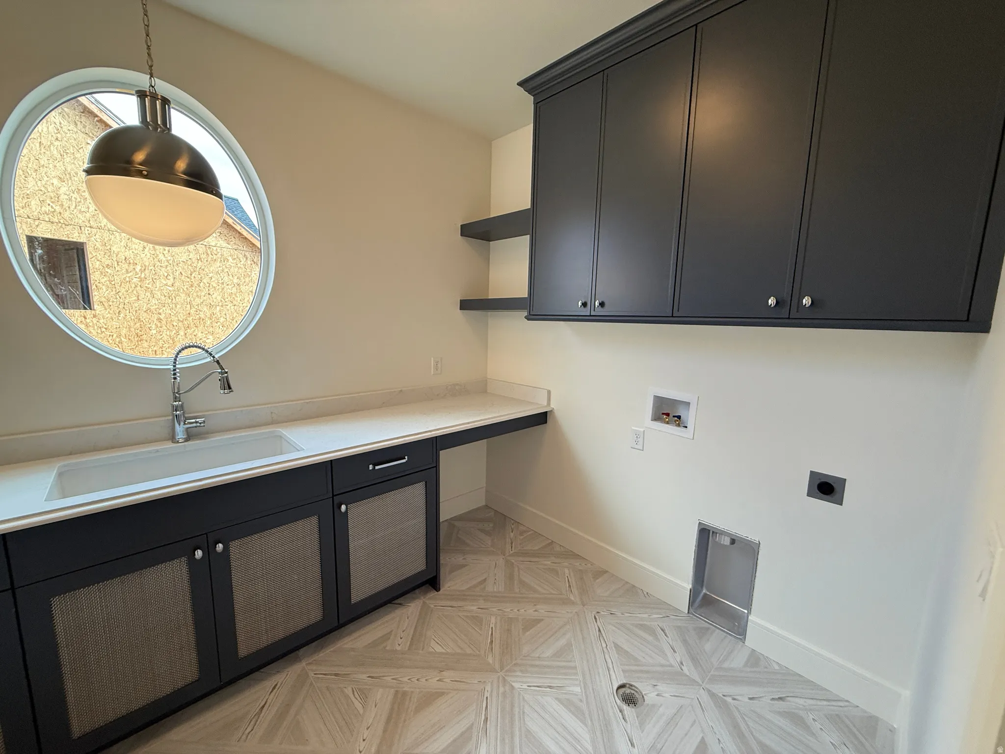 Round window with pendant lighting, integrated sink, wood-finish flooring, and built-in cabinetry