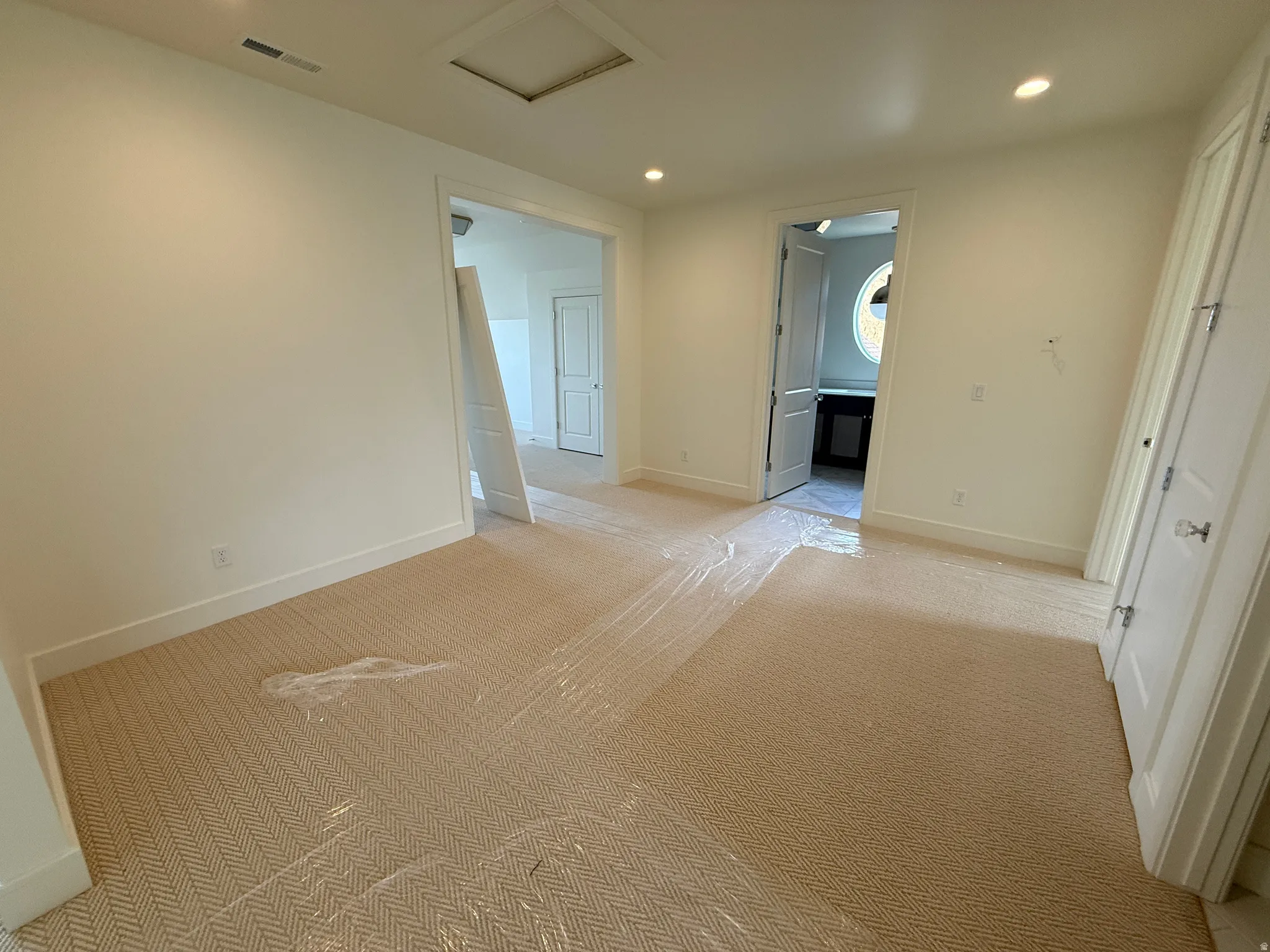 Recessed ceiling lighting, light-toned wall finishes, and patterned carpeting