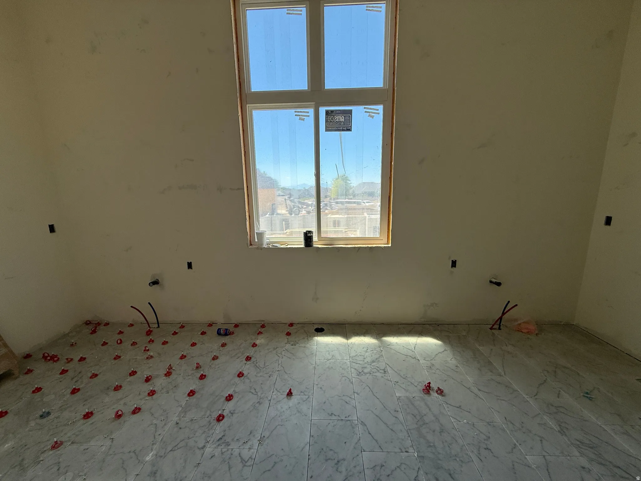 Large double-pane window, pre-wired electrical outlets, plumbing rough-ins, and marble-look tile flooring