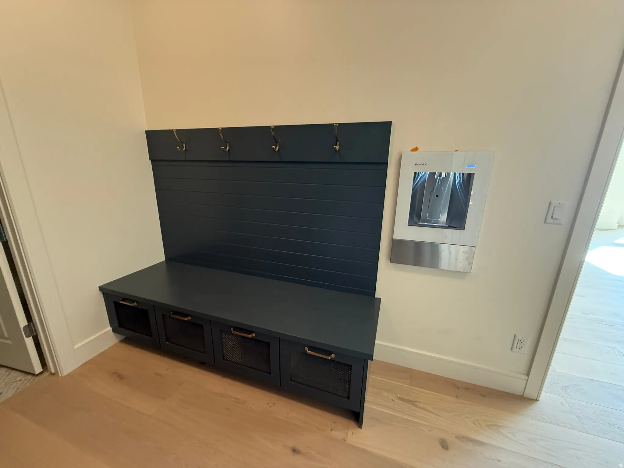 Built-in mudroom bench with coat hooks, storage cubbies, and wood-finish flooring
