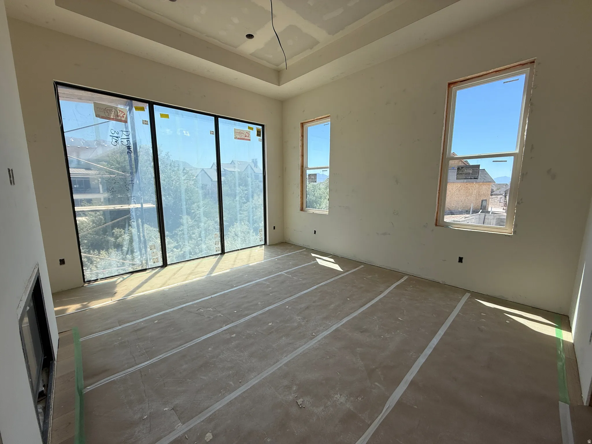Spacious room featuring a large multi-panel window, two additional windows, a tray ceiling, and a built-in fireplace opening