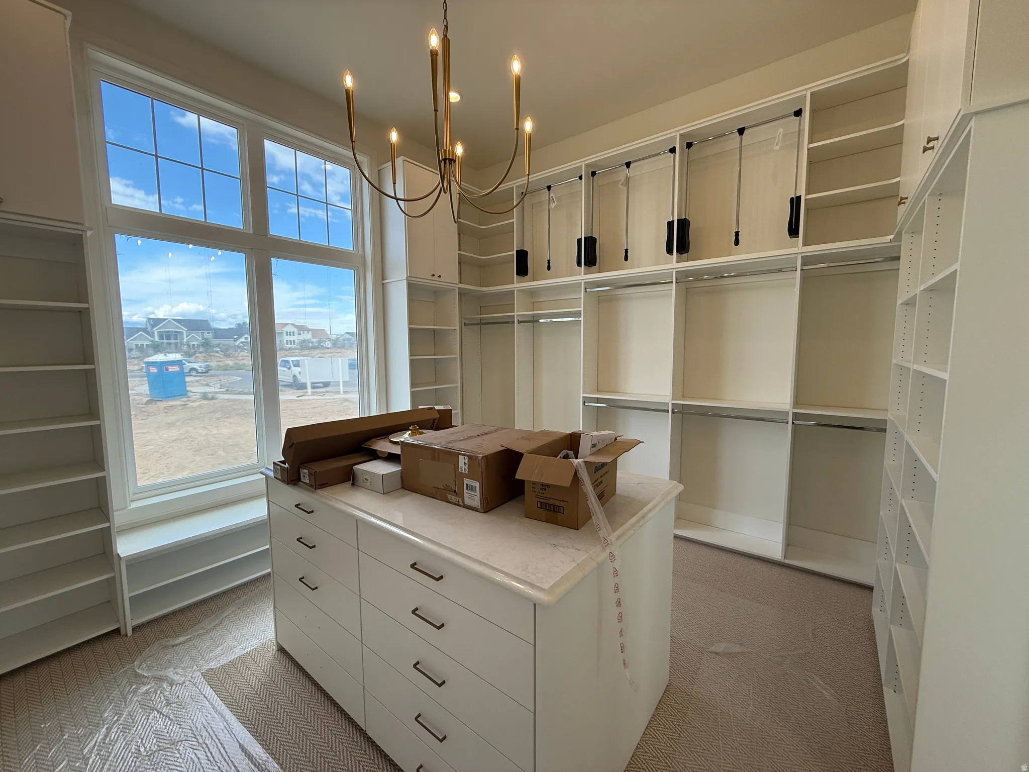 Expansive custom closet featuring built-in shelving, hanging rods, an oversized center island with drawers, and a large multi-pane window